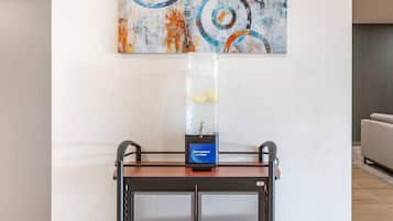Eine moderne Hotelhalle mit Wasserspender, abstrakter Kunst an der Wand und einer Sitzgelegenheit.