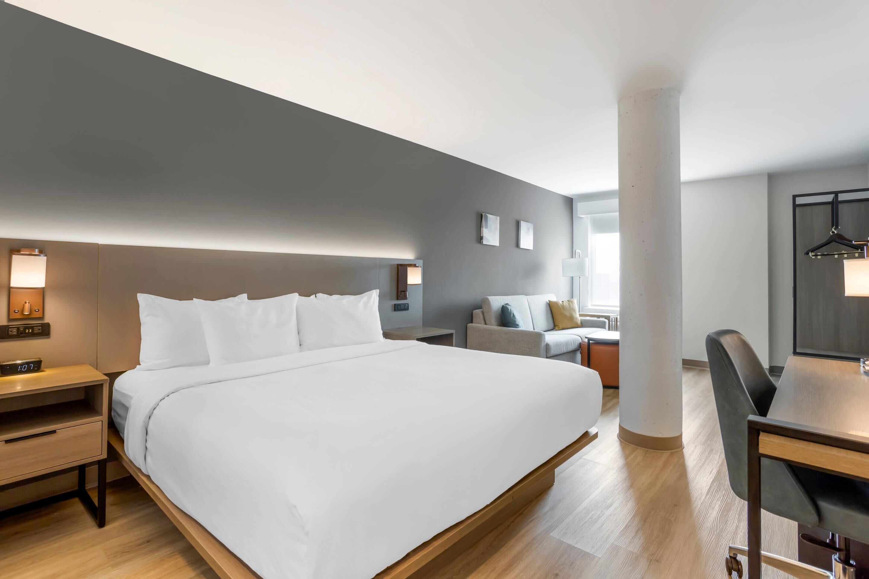 Een moderne hotelkamer met een groot bed, nachtkastjes, een bureau en een bank.