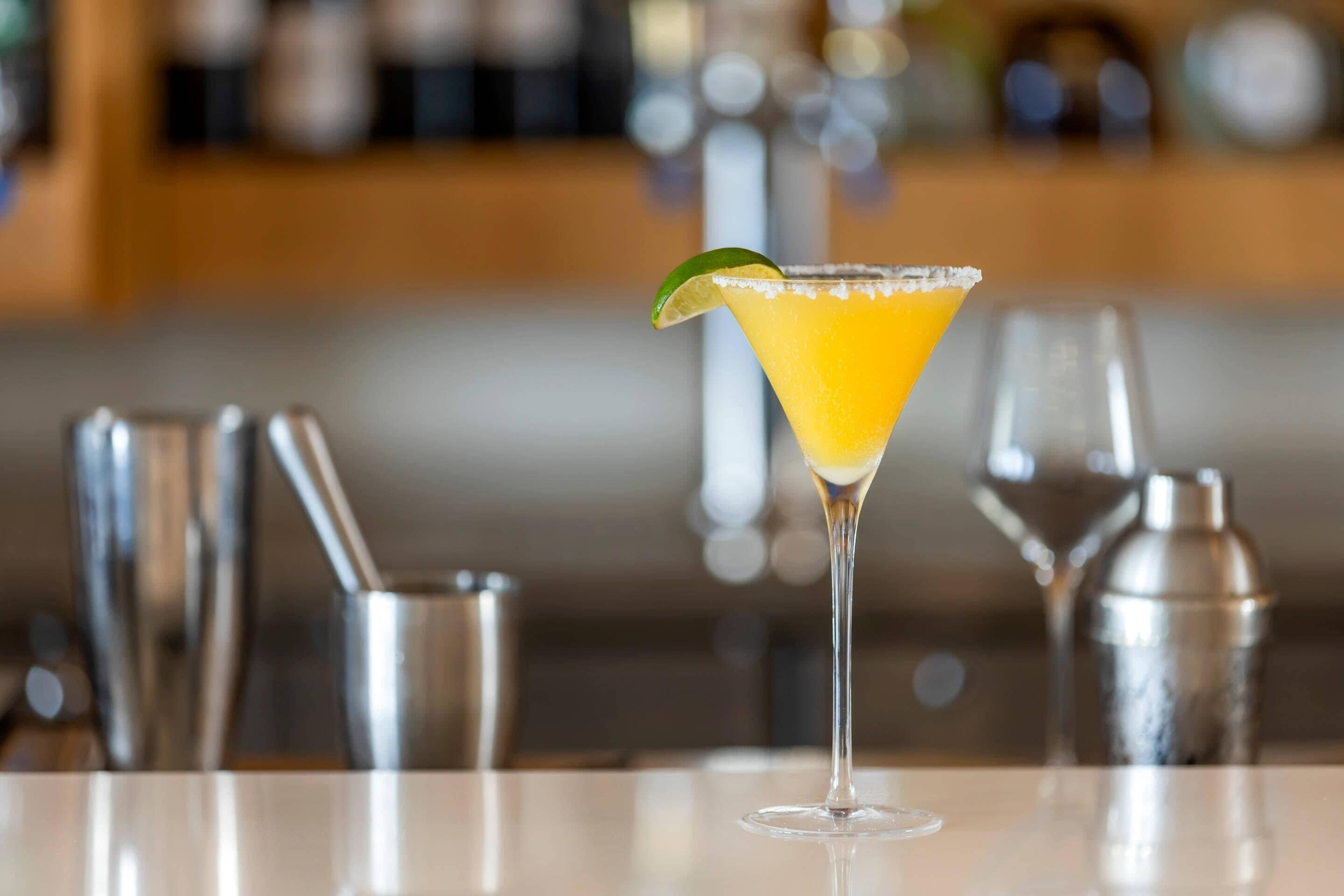 A cocktail glass with a lime garnish on a bar counter.