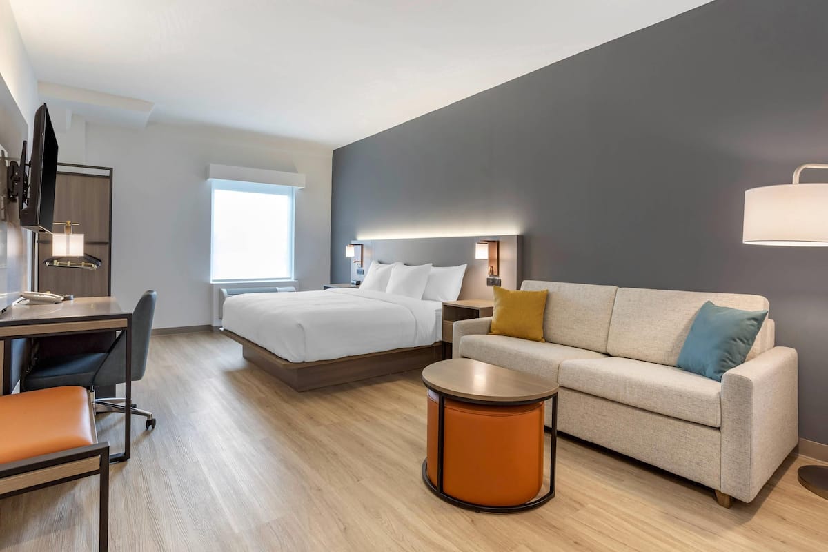 Une chambre d’hôtel moderne équipée d’un lit, d’un canapé, d’un bureau et d’une table ronde.