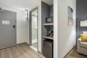 Una habitación de hotel compacta con kitchenette, microondas, cafetera y refrigerador pequeño.