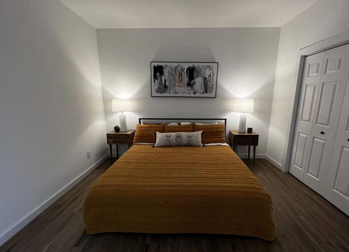 Een slaapkamer met een groot bed, twee nachtkastjes en een deur.