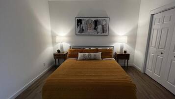 Een slaapkamer met een groot bed, twee nachtkastjes en een deur.