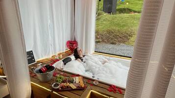 Relax in a serene space with a grassy view, a cozy seating area, and a plush bed.