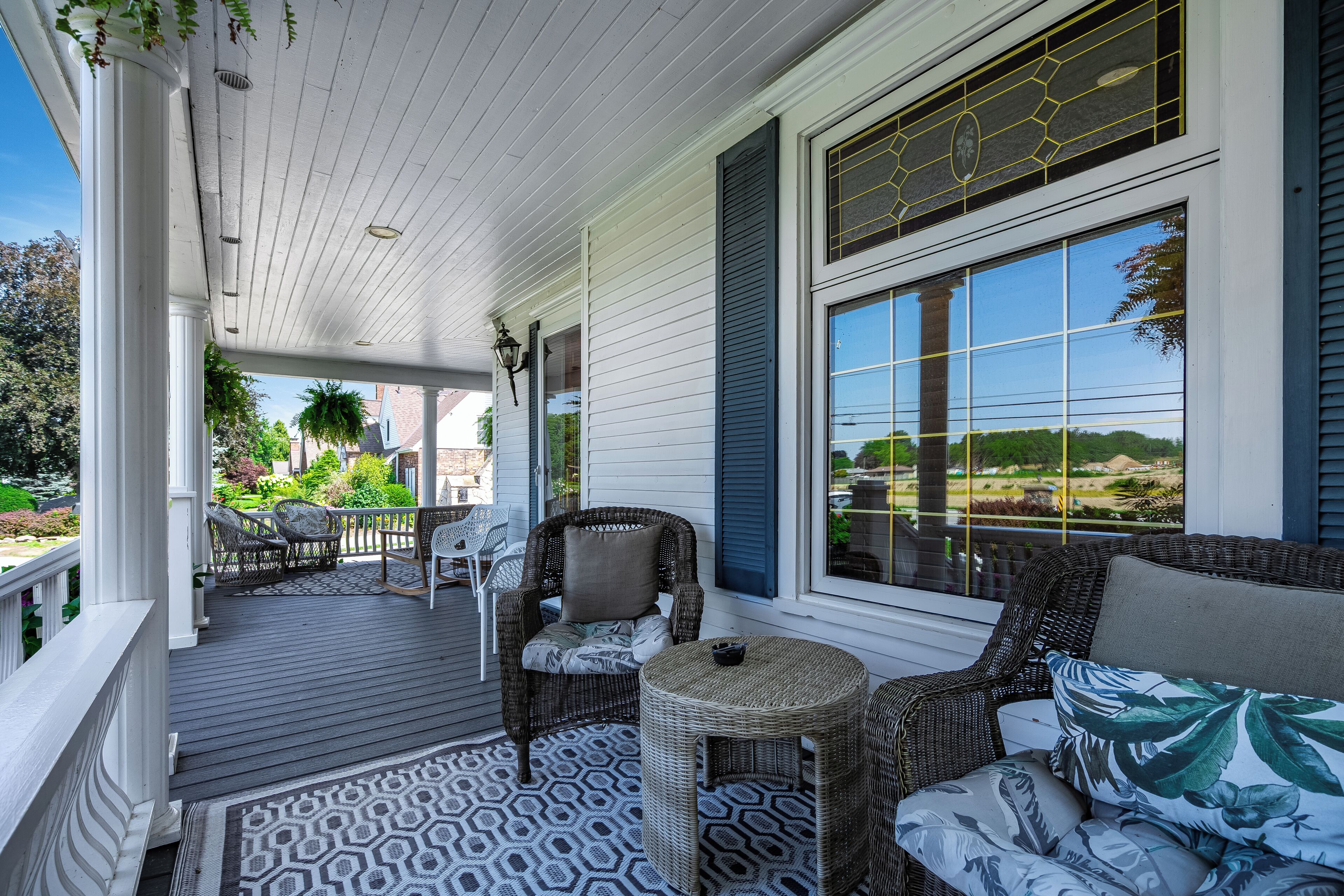 A covered porch with wicker furniture, a patterned rug, and a view of the landscape.