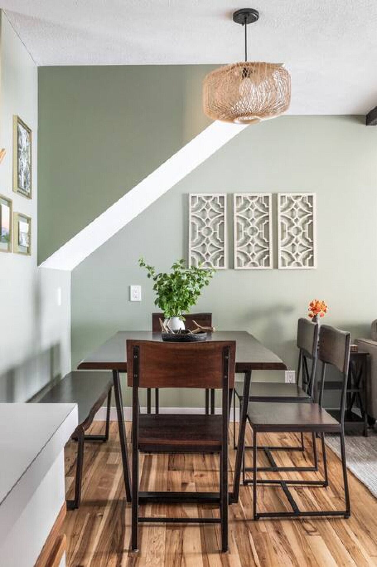 A dining area with a wooden table, chairs, and a hanging light fixture.