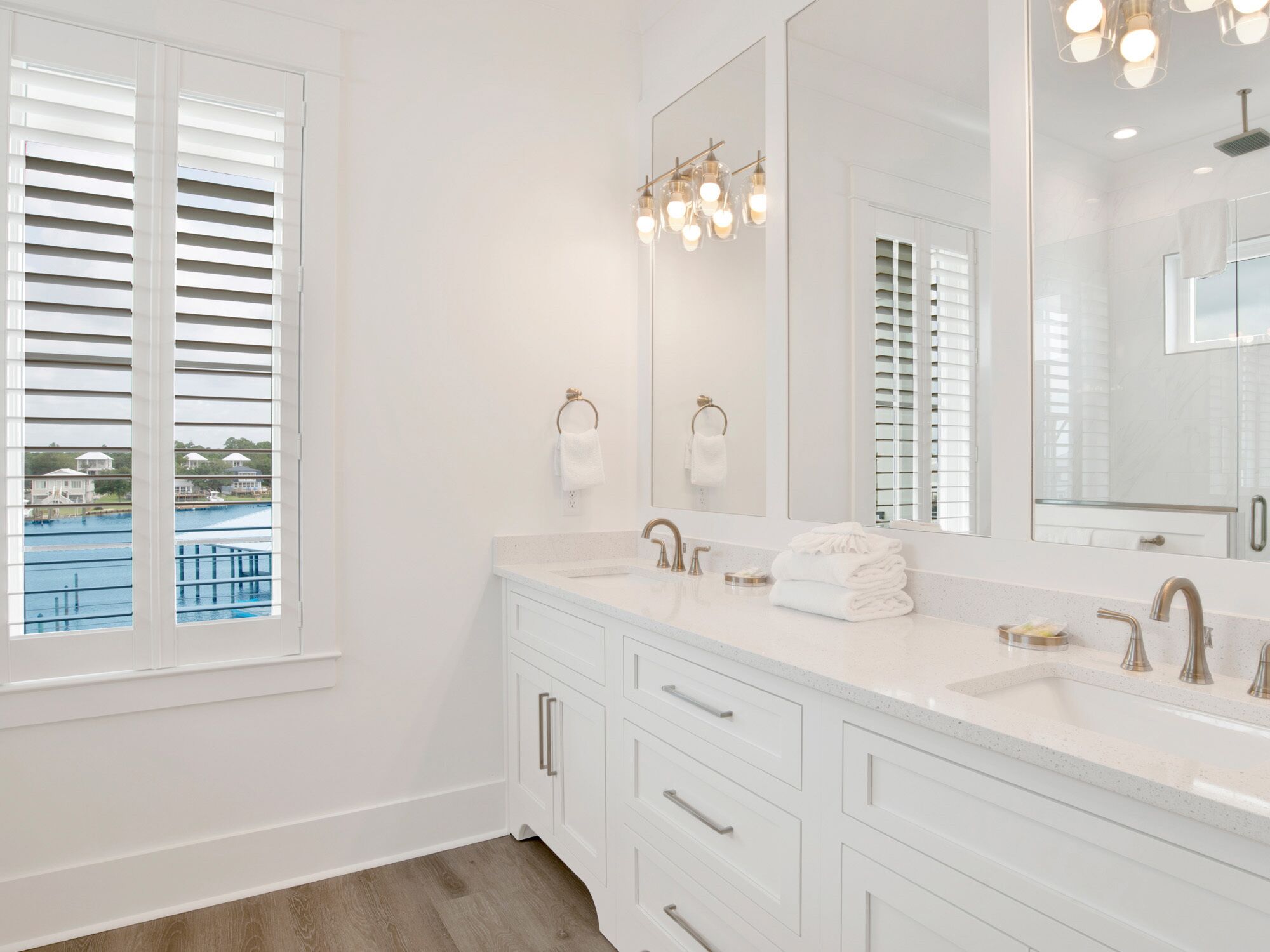 A bathroom with a large mirror, two sinks, and a window with blinds.