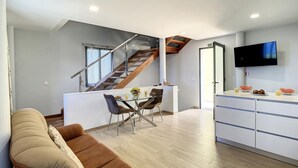 Un espacio habitable moderno con cocina, comedor y una escalera que sube a un nivel superior.