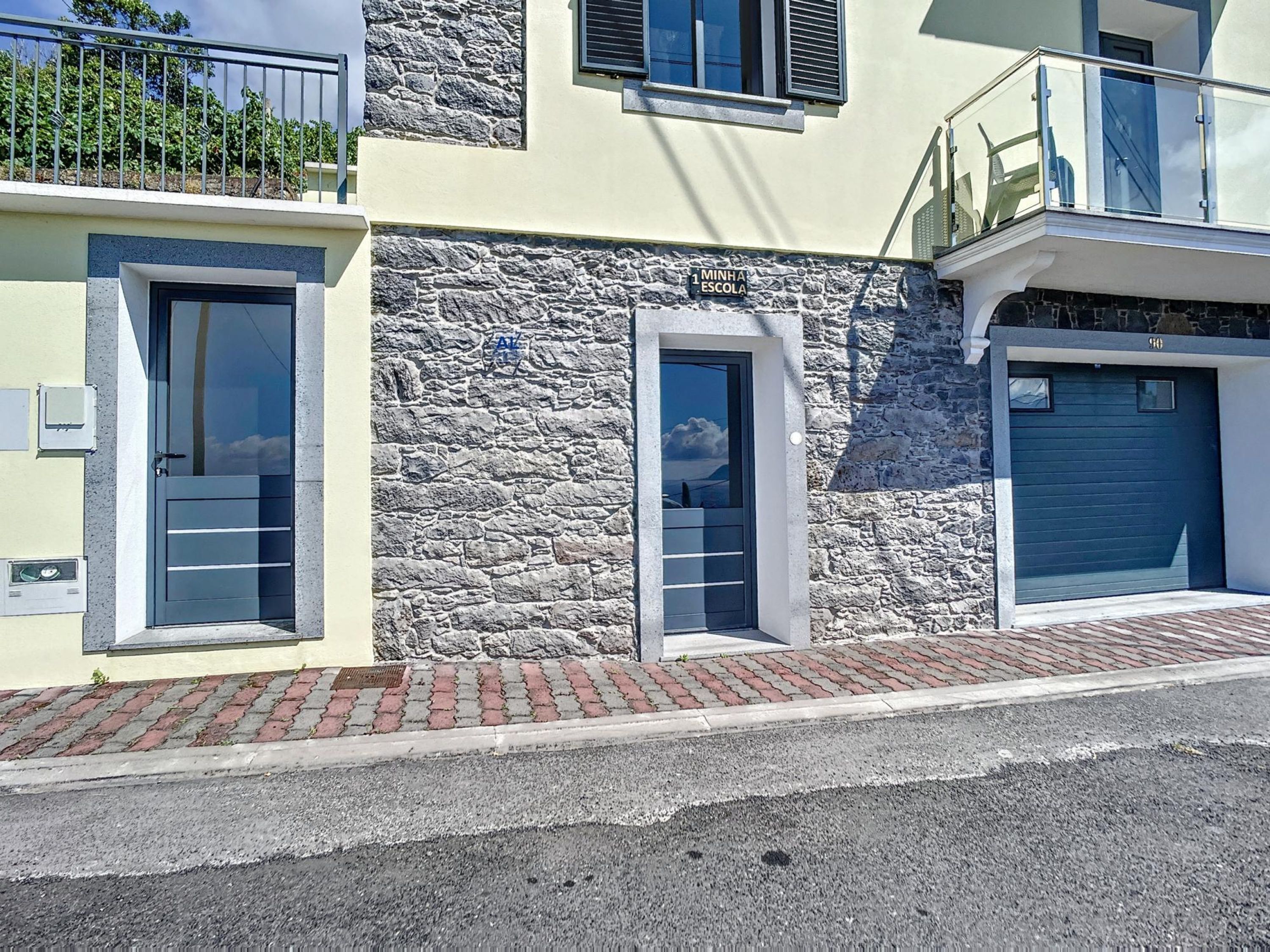 A modern building with a stone facade, two doors, and a garage.