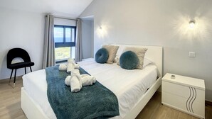 Un dormitorio moderno con una cama grande, dos luces empotradas, una mesita de noche y vistas al exterior.