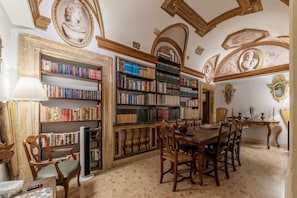 A library with bookshelves, a dining table, chairs, and classical architectural details.