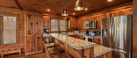 Une cuisine avec des meubles en bois, un réfrigérateur en acier inoxydable et un plan de travail en granit.