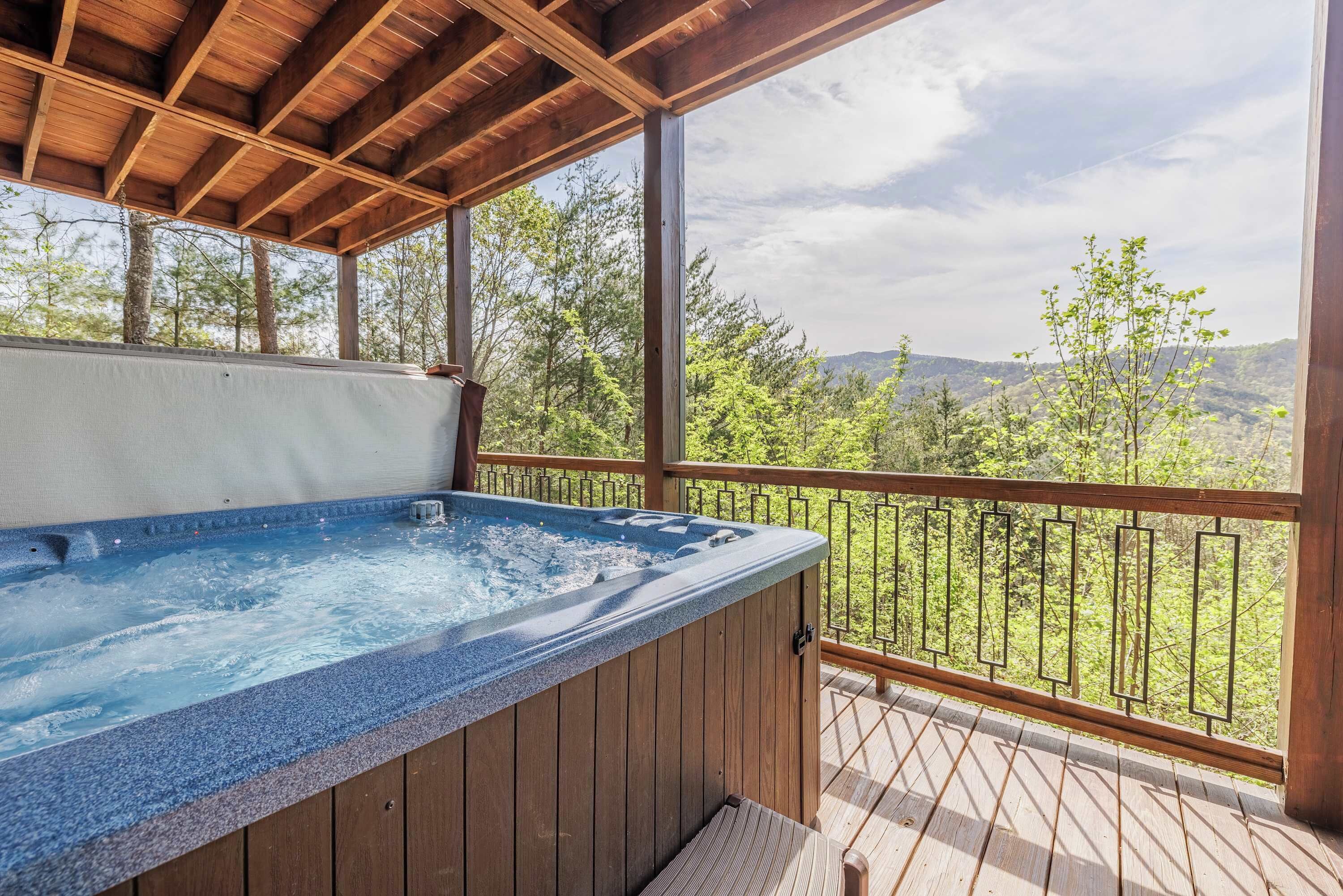 Een hottub op een houten terras met uitzicht op bomen en bergen.