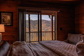 Ein Ferienhauszimmer mit großem Fenster und Blick auf einen bewaldeten Berg.
