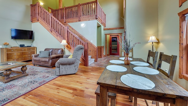 A spacious living room with a wooden staircase, a dining table set with placemats, and a leather sofa. - Slaty Fork Home ~ 6 Mi to Snowshoe Mountain Resort (Slaty Fork)
