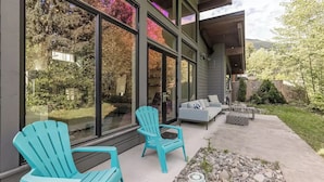 A modern house with large windows, outdoor seating, and a garden. - Large Modern Home in Squamish (Squamish)