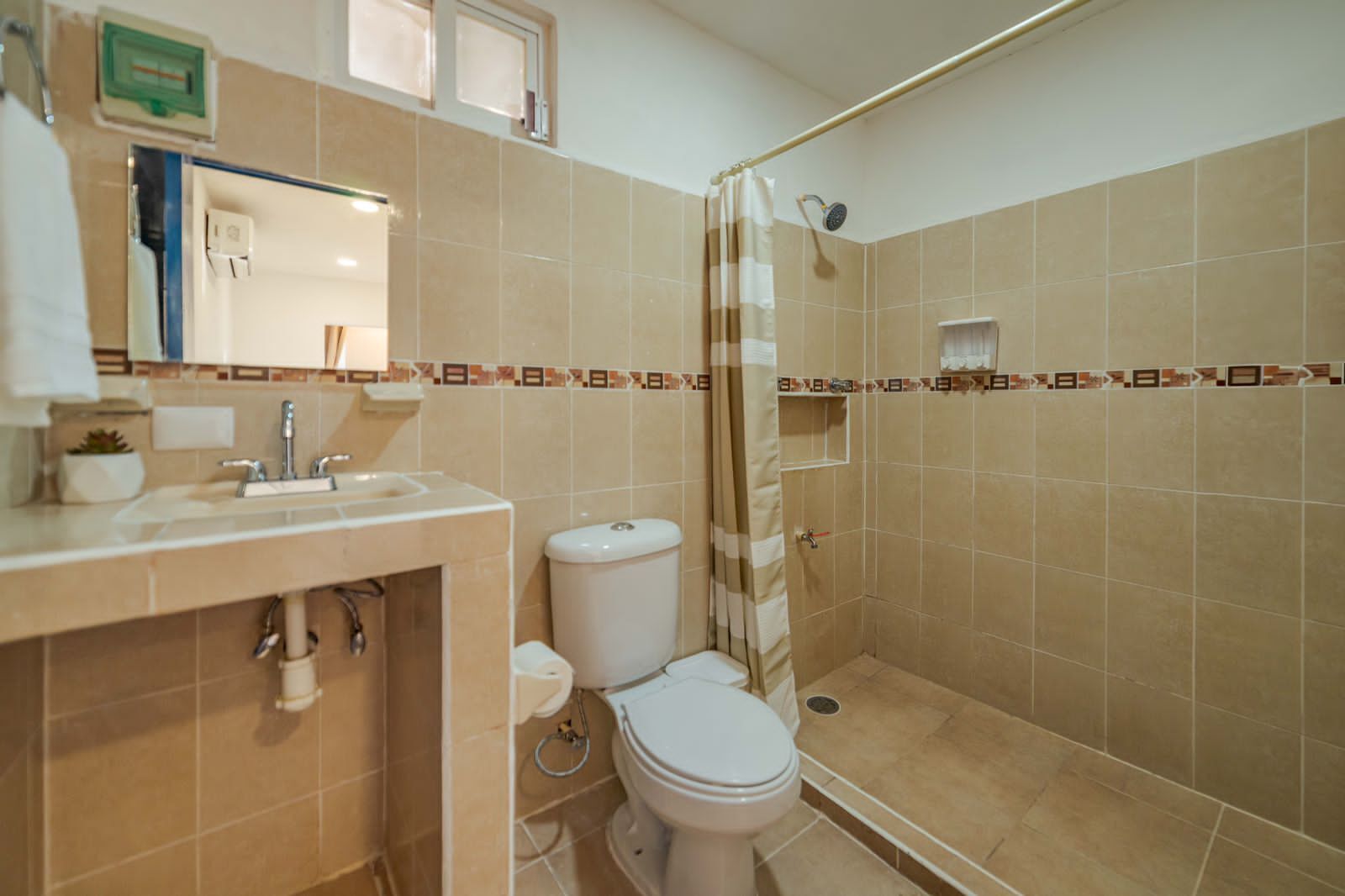 Un baño con inodoro, lavamanos y zona de ducha.