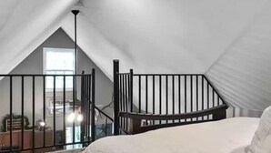 Ein Schlafzimmer im Dachgeschoss mit hohen Decken, geneigtem Dach, einem Holckrippenbett und Blick auf einen Balkon.