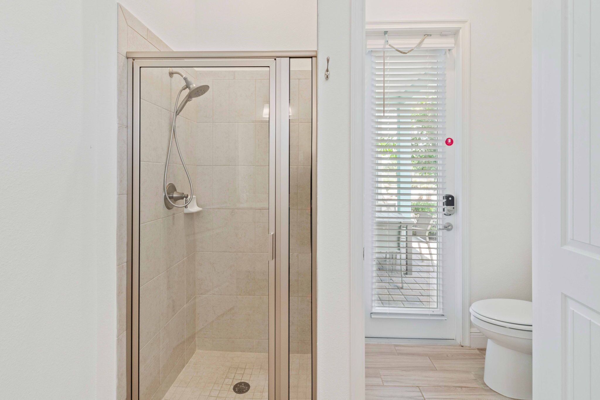 A modern bathroom with a glass-enclosed shower, a toilet, and a door with a window.