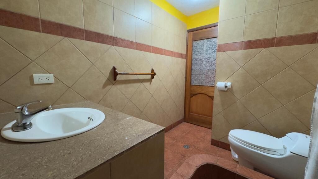 A bathroom with a sink, toilet, and a towel rack.