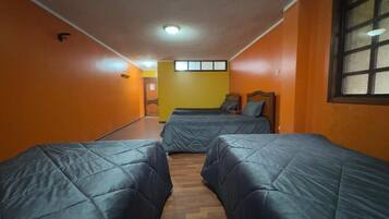 A room with two beds, a wooden floor, and orange walls.