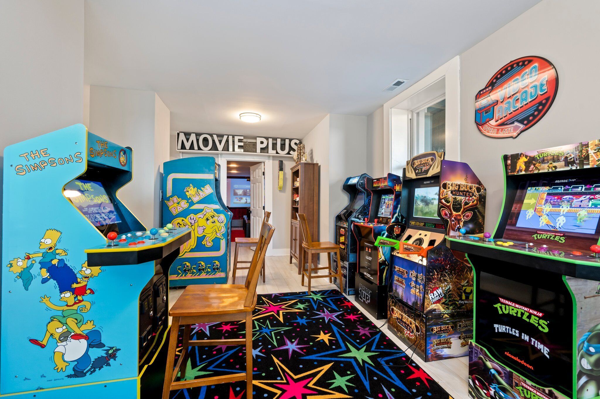 Una habitación con juegos de arcade, un letrero 'MOVIE PLUS' y un letrero 'VICO ARCADE'.