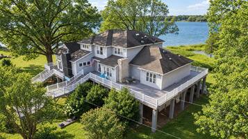 Une grande maison dotée de plusieurs terrasses et offrant une vue sur un lac.