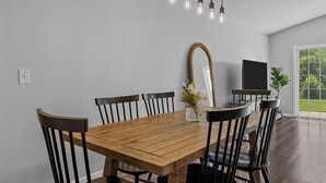 Una sala da pranzo con un tavolo in legno, sedie nere, uno specchio e un televisore.