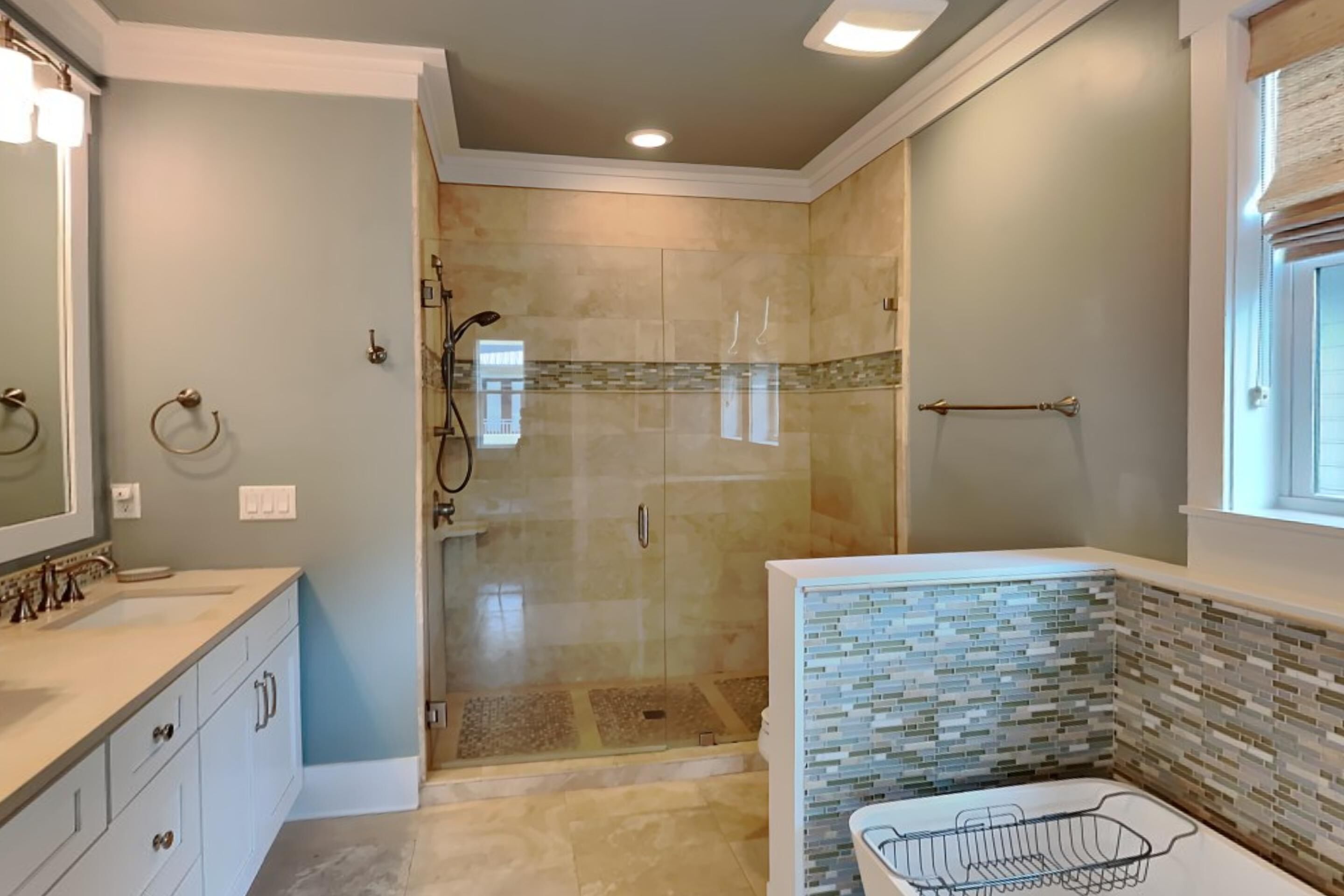 Une salle de bain moderne avec une douche à parois de verre, un meuble-lavabo avec un miroir et un mur recouvert de carreaux.