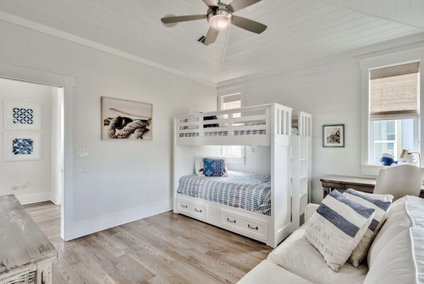 A bedroom with a bunk bed, a desk, and a chair.