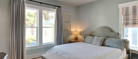 A bedroom with a bed, a bench, a nightstand with a lamp, and a ceiling fan.
