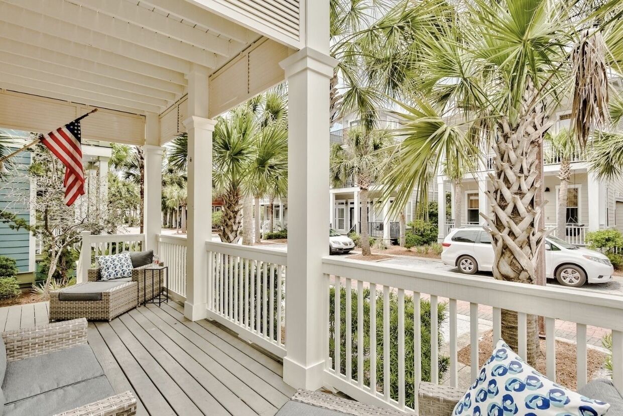 A porch with a white railing, a wicker sofa, and an American flag.