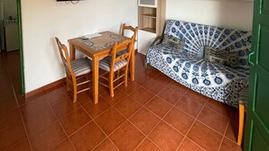 Un espacio habitable compacto con una mesa de comedor, sillas, un sofá, un televisor y un mueble pequeño.