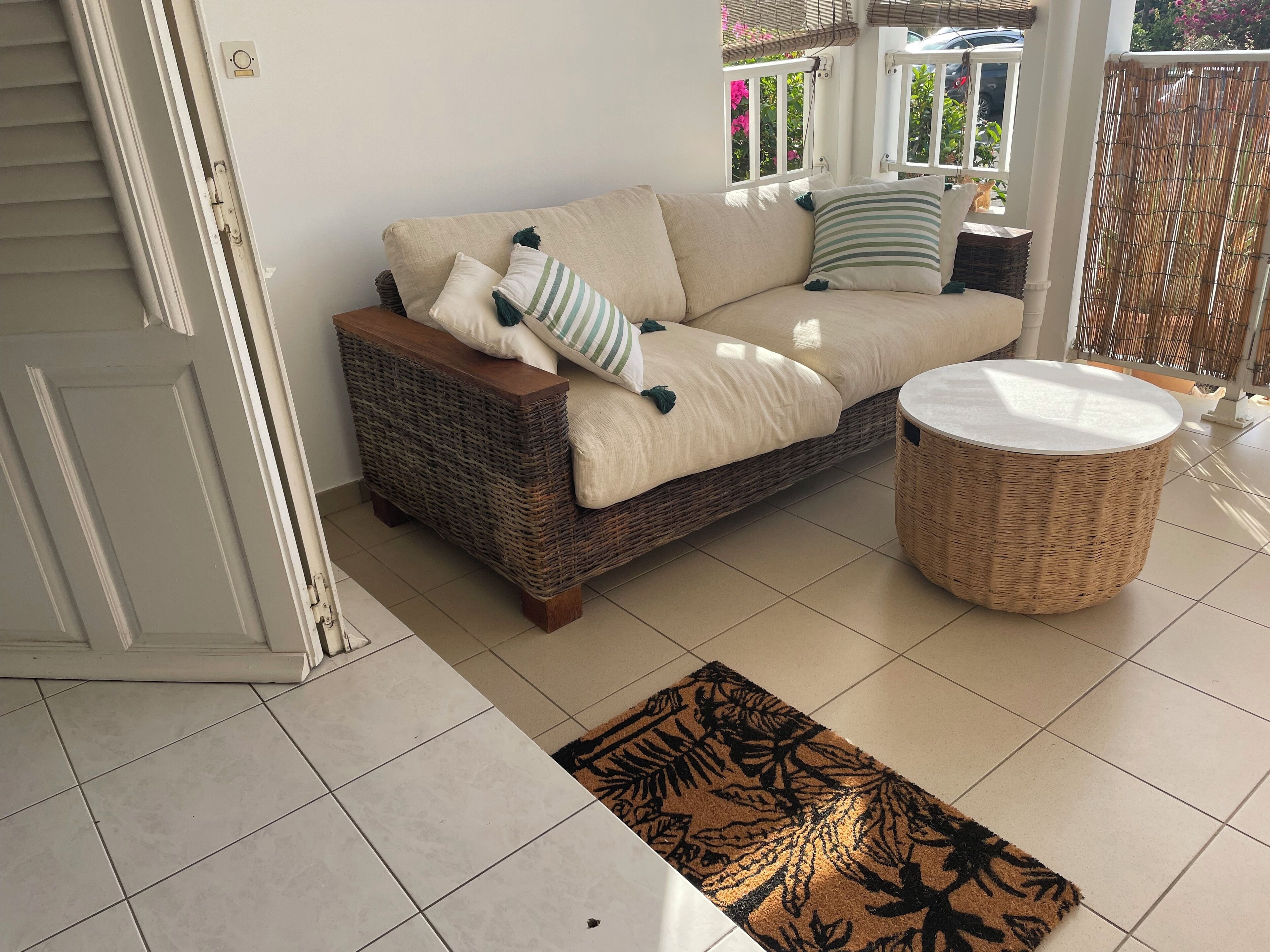 A living room with a wicker sofa, a round wicker table, and a patterned rug.