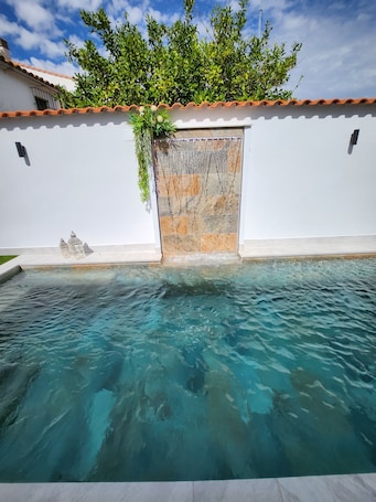 Una piscina al aire libre, sillones reclinables de piscina