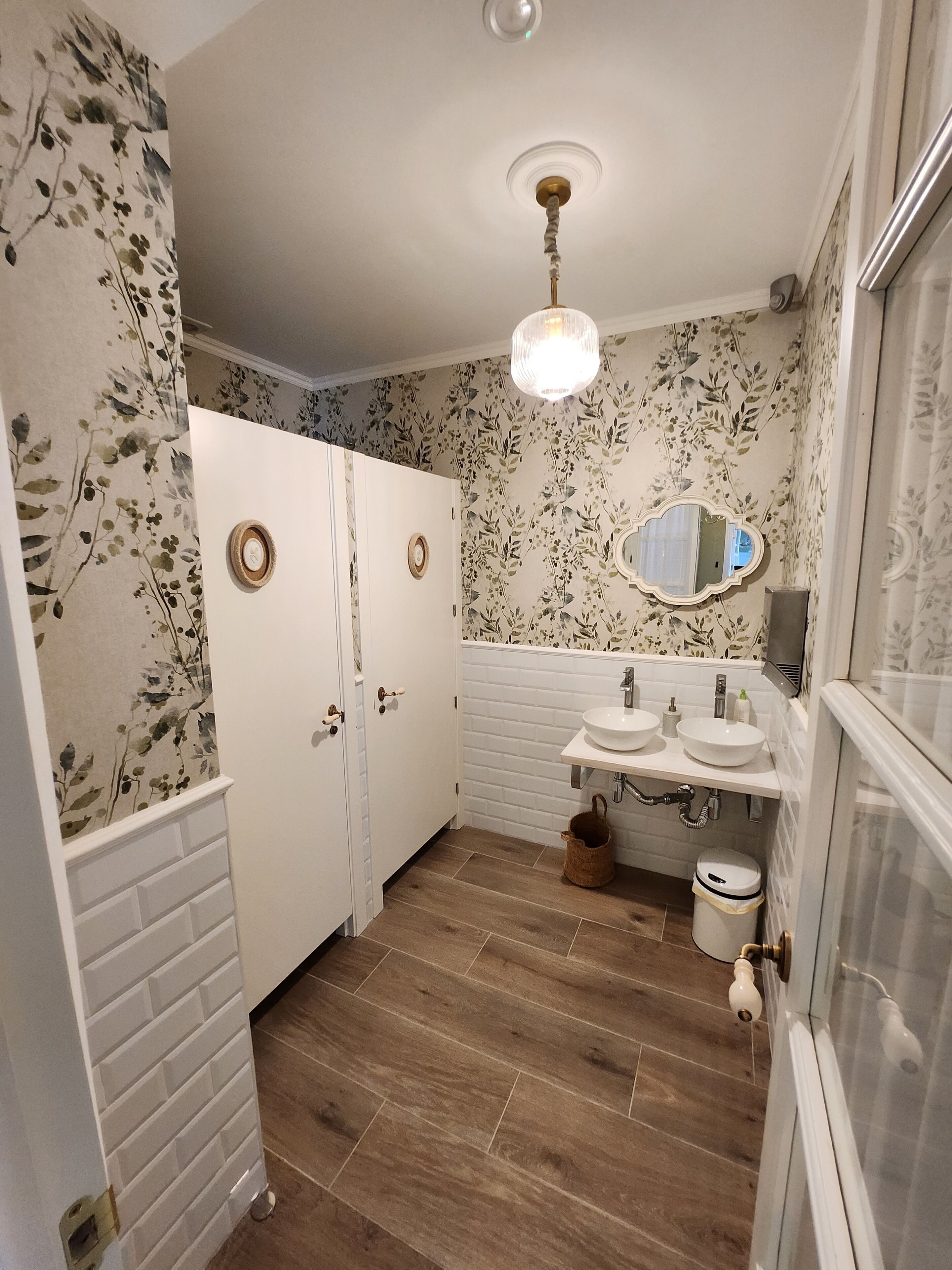 Un baño con tocador blanco, dos lavamanos, un espejo y suelo de madera.