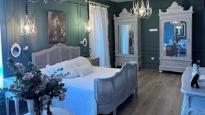 Ein Schlafzimmer mit einem großen Bett, zwei verzierten Kommoden, einer Pendelleuchte und einem Spiegel.
