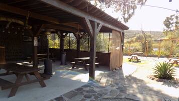A covered outdoor area with picnic tables and a stone-paved walkway.