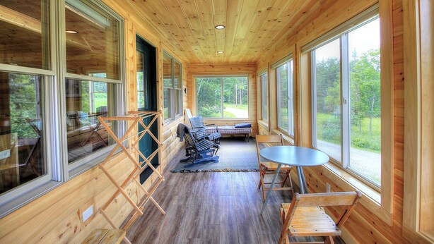 Ein Holzblock-Interieur mit großen Fenstern, einer Sitzecke mit Tisch und Blick ins Freie.