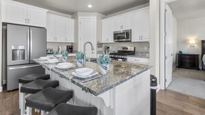 A modern kitchen with white cabinets, a granite countertop, and stainless steel appliances. - Escondido 1149, Desert Bloom Retreat|Grill, Smart TV, Xbox 360, 2 Laundry Rooms, SLP 14 (Washington)
