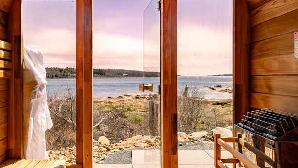 A wooden cabin with a view of a lake and rocky shoreline. - Dreamy Oceanfront Escape Hot tub & Sauna (South Shore)