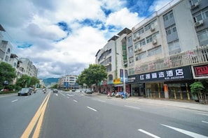 A street view with a hotel named 'Hong Kong Travel Hotel' on the right, featuring a signboard with contact information. - Xian Biao Business Hotel (Wuping)