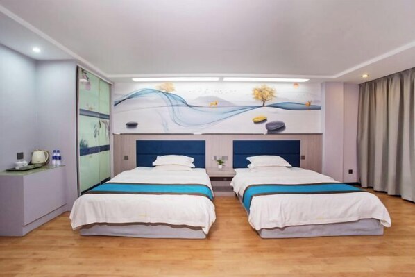Ein Hotelzimmer mit zwei Betten, einem Schreibtisch mit Lampe und Wandgemälde.