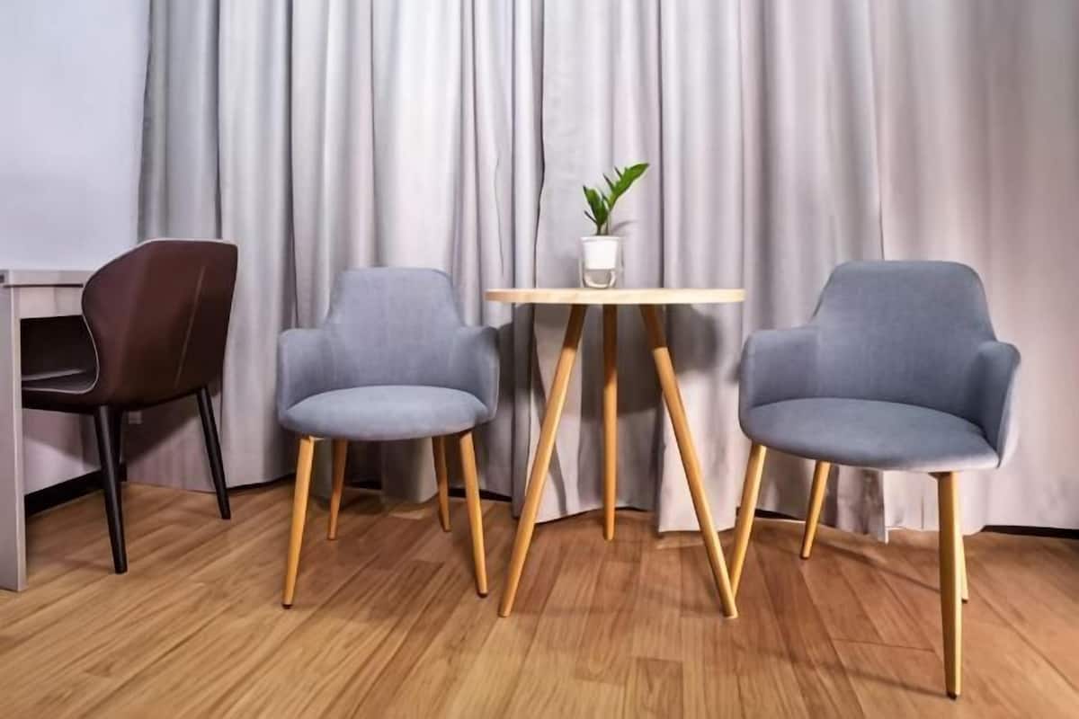 A room with a wooden floor, two grey chairs, a small wooden table, and a potted plant.