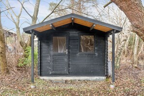 A small, black wooden cabin with a pitched roof, a single door, and a window.