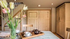 A dining table with a tray, a teapot, and a cup. There is a vase with tulips on the table. - Gardiners Cottage Barn, Eye (Stoke Ash)
