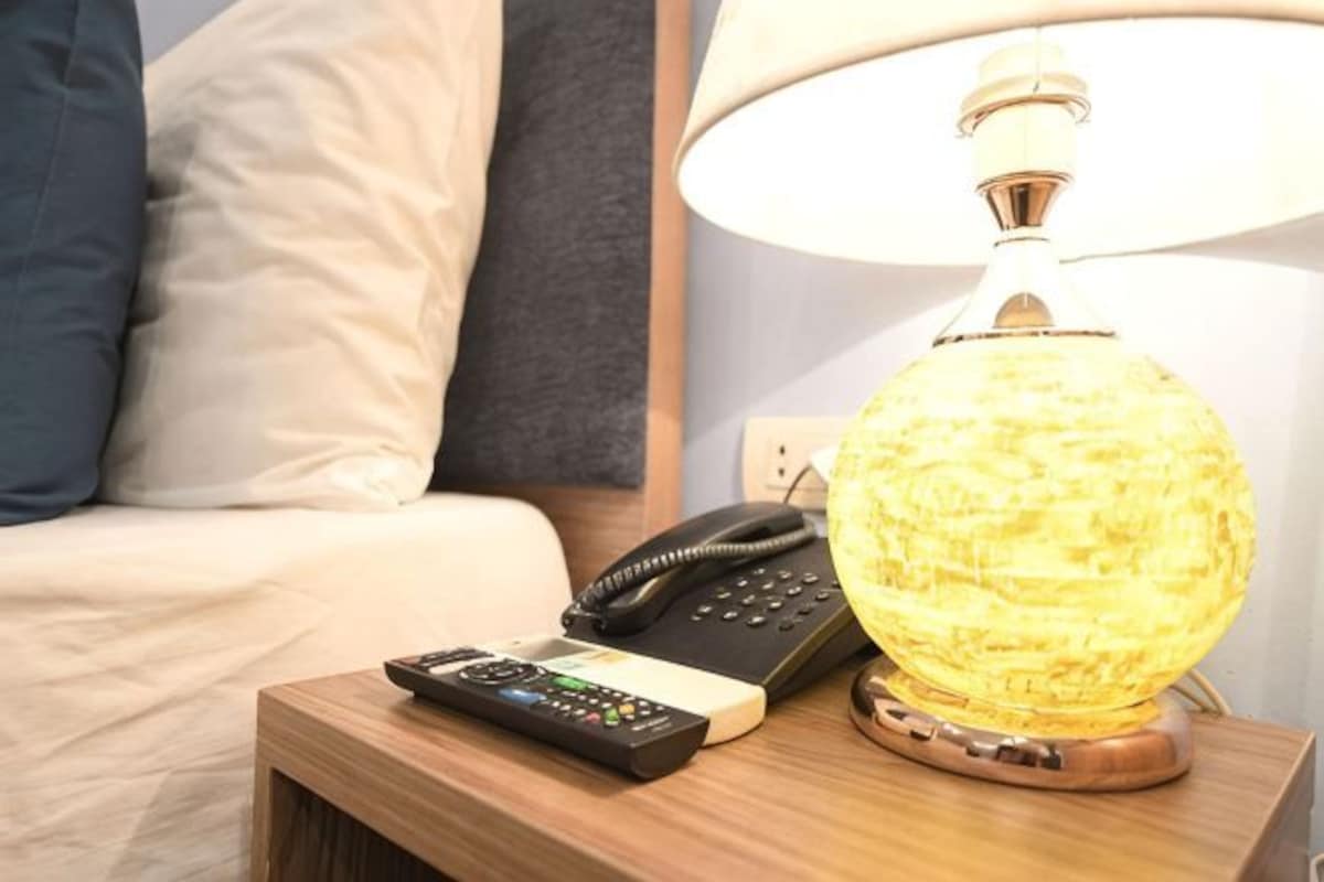 Une table de chevet avec une lampe, un téléphone et une télécommande.