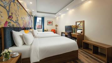 A hotel room with a large bed, a desk, a television, and a decorative wall mural.