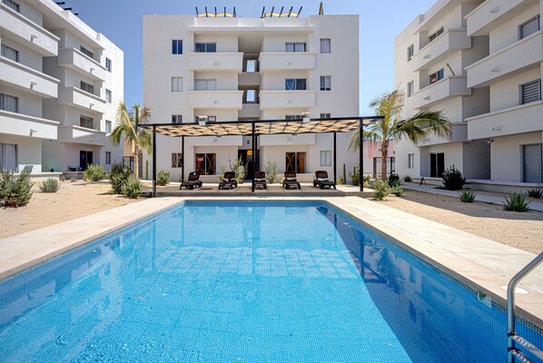 Relax by the hotel's central pool, surrounded by lounge chairs and a covered seating area.