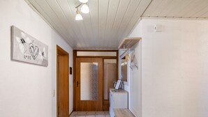 Ein Flur mit einer Holztür, einem gerahmten Kunstwerk an der Wand, einer Waschmaschine und einem Regal mit Gegenständen.
